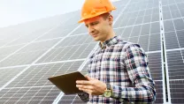 man looking at his tablet in front of a PV plant
