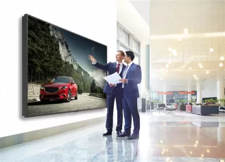 Two men looking at a large display in a car showroom