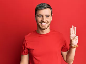 Man in red t-shirt counts to three with his fingers 