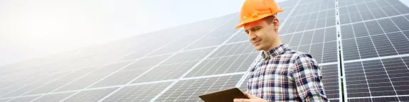 man looking at his tablet in front of a PV plant