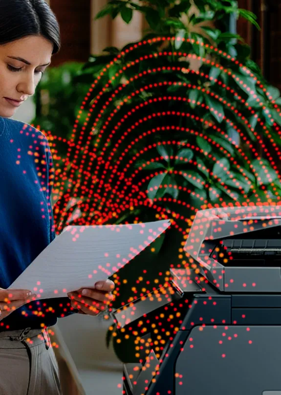 Woman standing in front of a Sharp MFP looking at a document